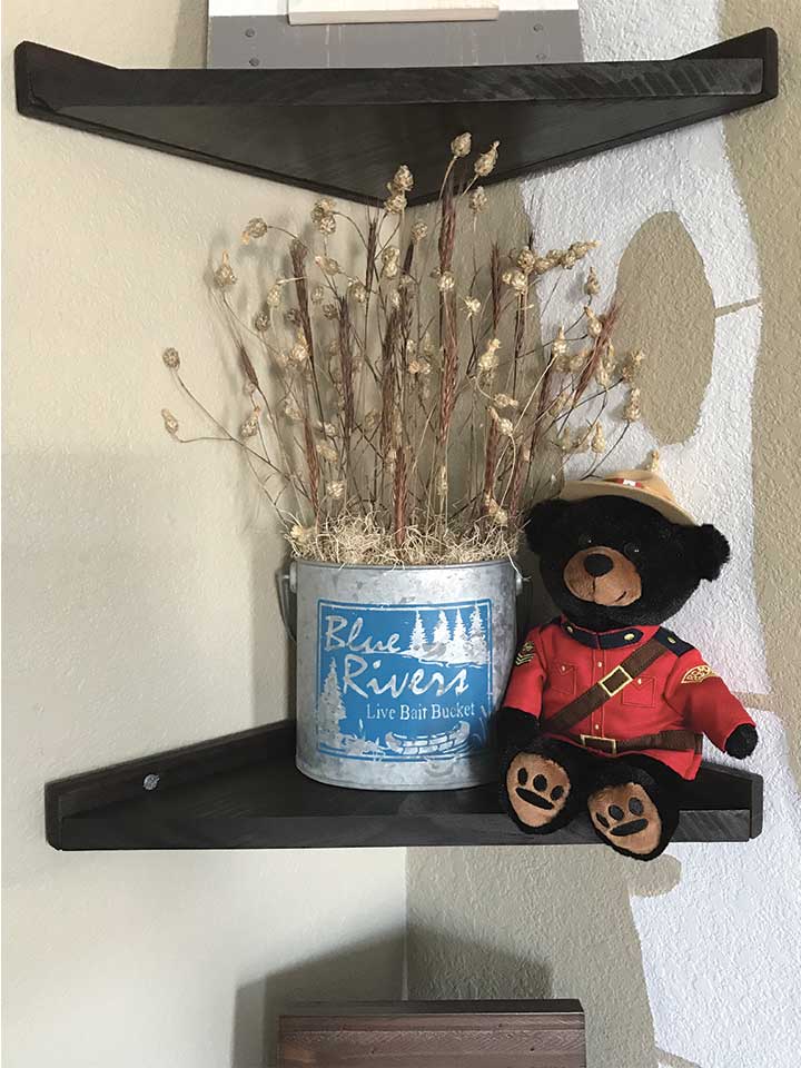 DIY wood corner shelves with a Canadian Mountie bear and galvanized metal pail fill with dried floral.