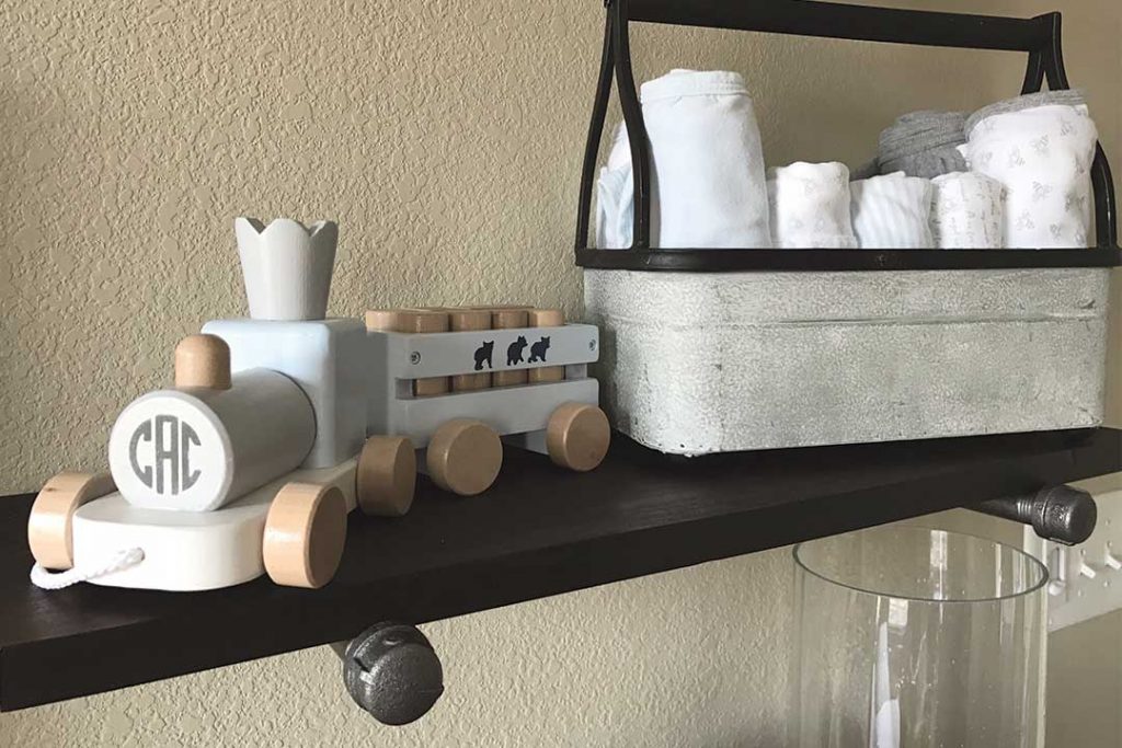 DIY industrial pipe shelf on nursery wall