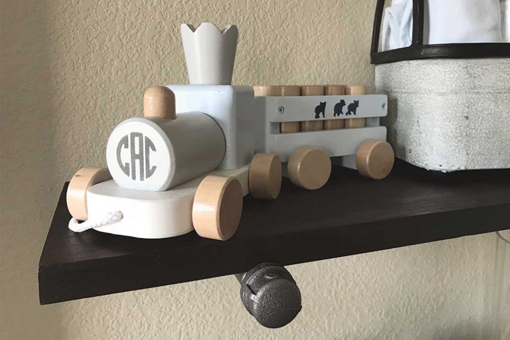 wood train on top of DIY industrial pipe shelf in nursery