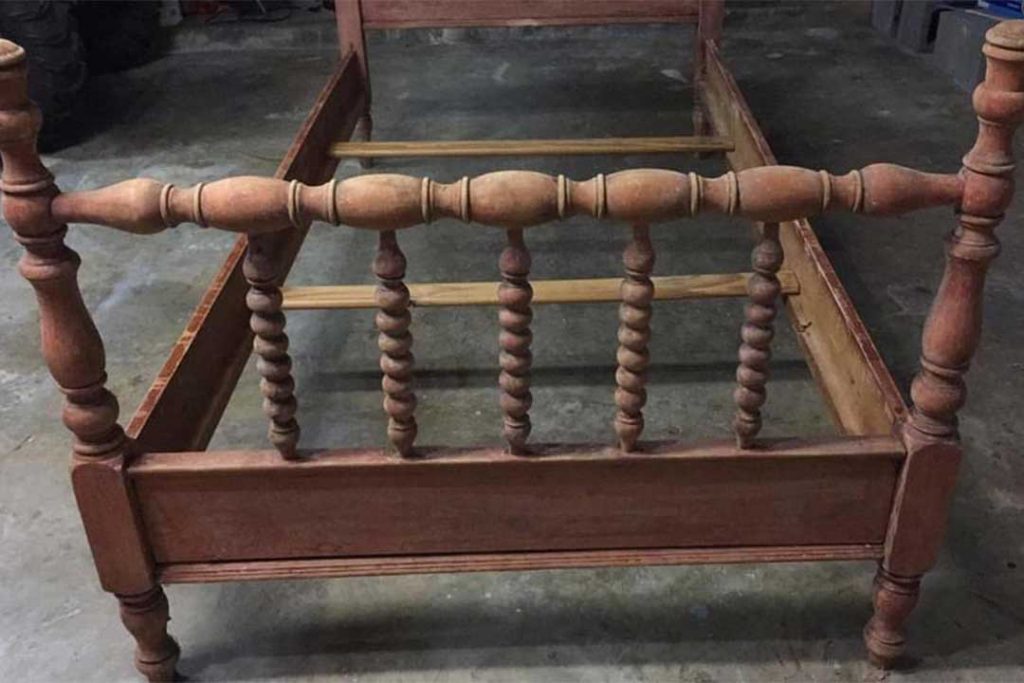 antique Jenny Lind bed with uneven finish due to stripping
