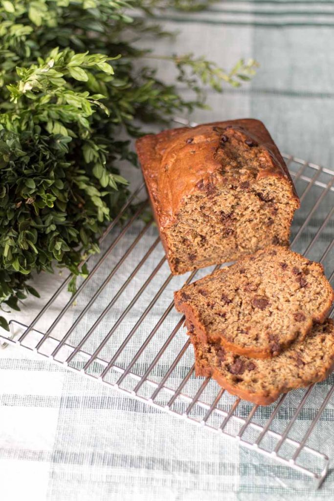 einkorn banana bread sliced on a cooling rack with boxwood wreath behind
