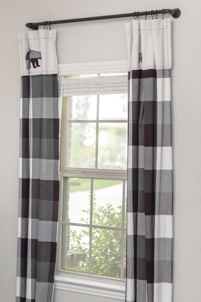 black and white buffalo check woodland nursery curtains open and pulled to each side of window
