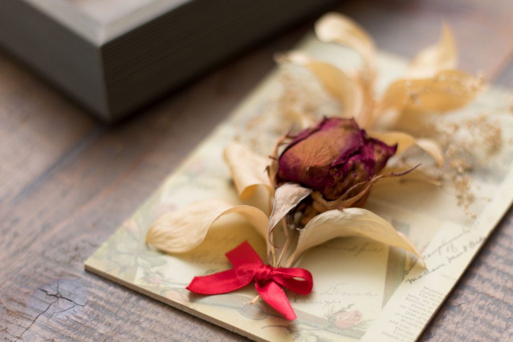 closeup of dried flowers with faded colors and ribbon tied in a bow at the base of the floral arrangement.