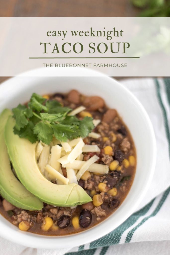 bowl of taco soup with a green and white tea towel on top of a farmhouse kitchen table