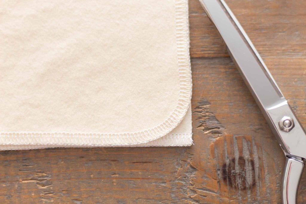 fabric folded in half with corners aligned and sewing shears on a farmhouse table