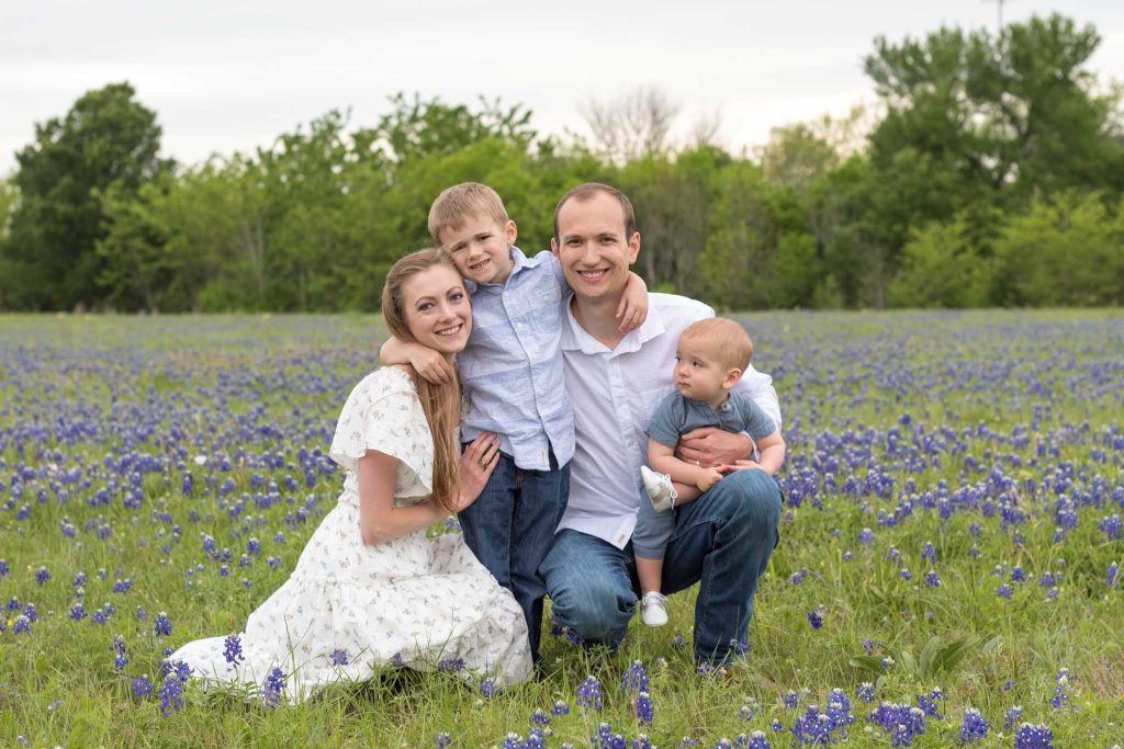 family of four dressed in white and blue in a field of bluebonnets
