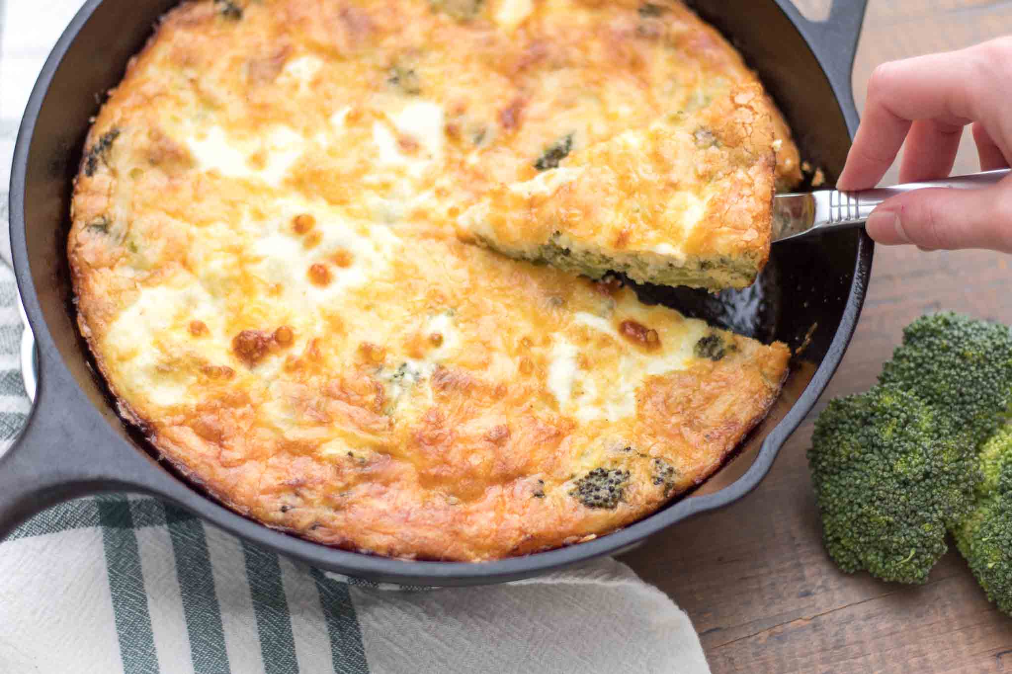 slice of crustless broccoli cheddar quiche being served out of a cast iron skillet