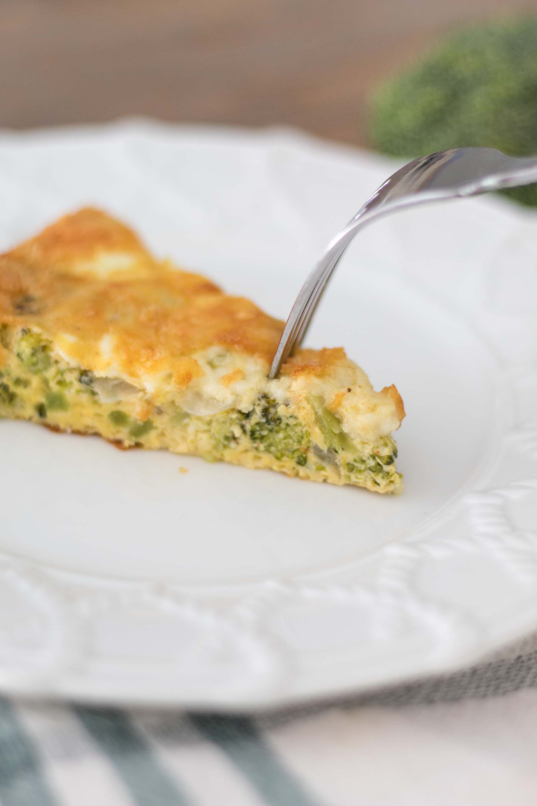 slice of broccoli cheese quiche with fork poking into it