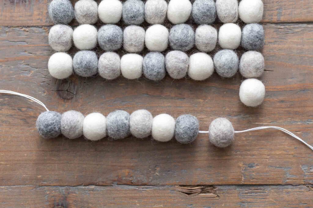 close-up of threading through the center of the wool felt balls to thread a row