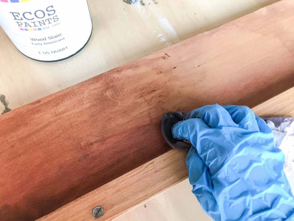 close-up photo of ecos paints stain application with a lint free staining rag on antique bed side rails