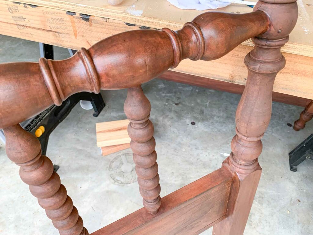 close-up photo showing the difference in finish between the stained portion and matte varnished portions on the spindles of an anqitue jenny lind headboard