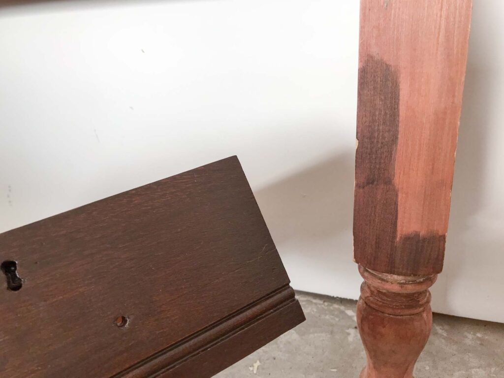 close-up of test stain samples on a flat surface of the jenny lind headboard to match the stain of an antique gentleman's dresser drawer next to it