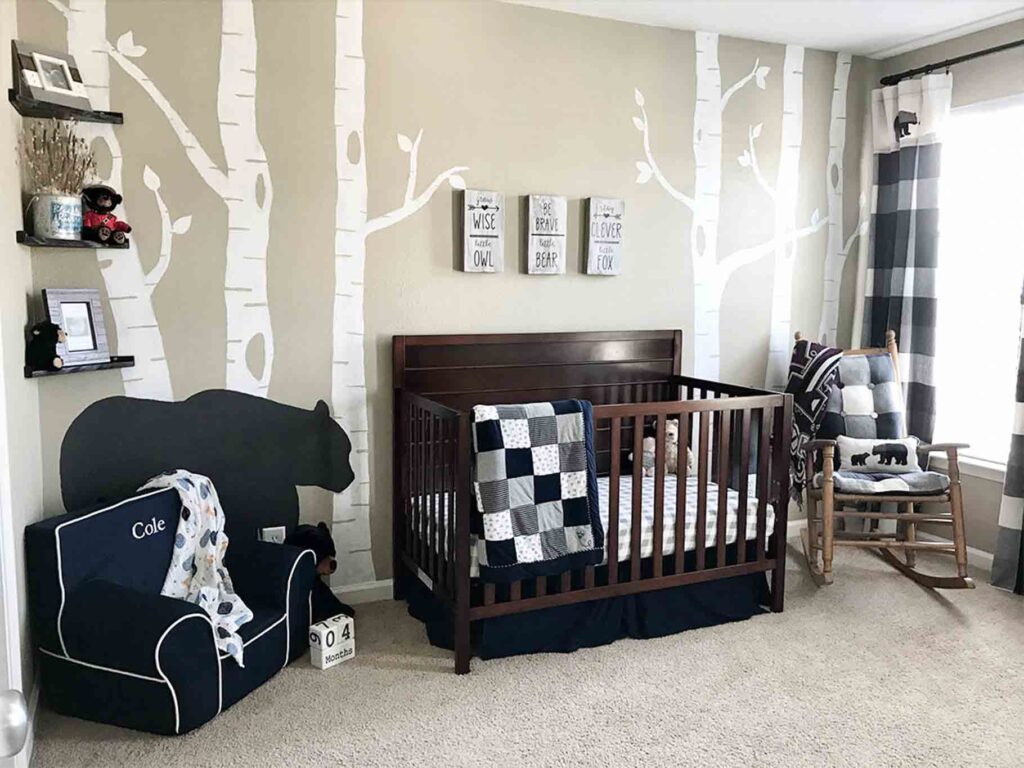 main wall of woodland nursery reveal showing the crib, reading corner, nursing nook, and full wall painting of white birch trees and black bears