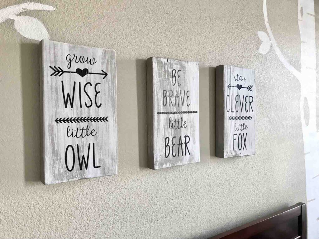 closeup of painted gray and white distressed wood signs that read "grow wise little owl, be brave little bear, stay clever little fox"