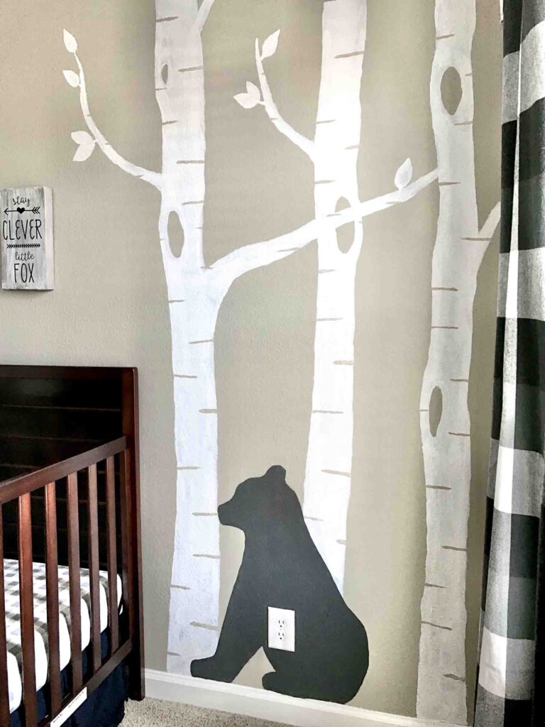 painted accent wall in woodland nursery with white birch trees and black bear