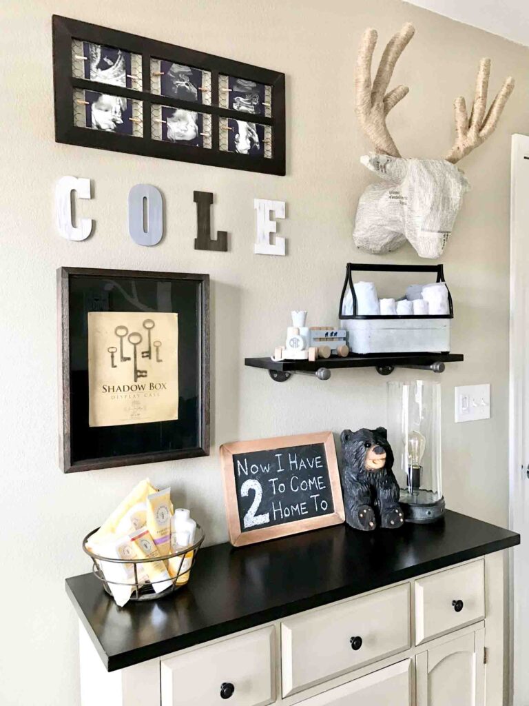 closeup of woodland nursery gallery wall with DIY projects: farmhouse ultrasound picture frame, paper mache deer head, industrial pipe shelf, and painted distressed wood letters