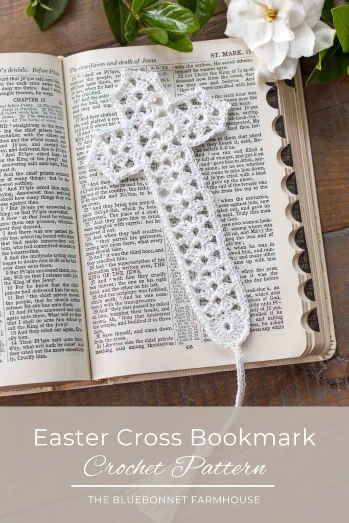 flat lay of a white lace crochet thread cross bookmark with tassel lying on top of an open bible in Mark chapter 15 next to a gardenia on top of a reclaimed farmhouse table. text reads "easter cross bookmark crochet pattern - the bluebonnet farmhouse"