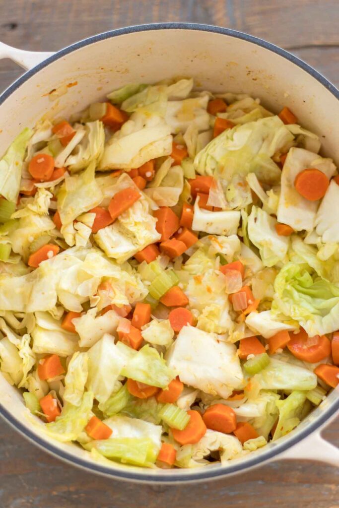roughly chopped cabbage and minced garlic with diced carrots, celery, and onion sautéed in a cast iron dutch oven