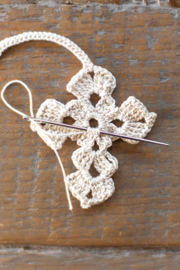 completed body of the cross bookmark with tapestry needle weaving in the loose ends of the white crochet thread