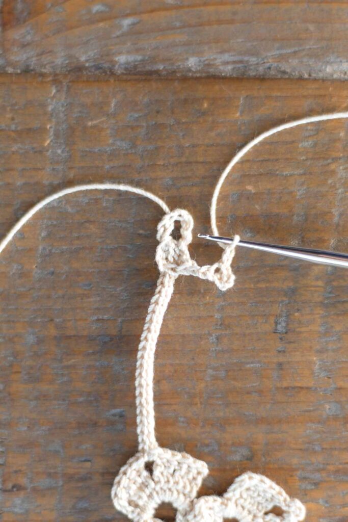 beginning of the crochet star and attaching it to the loop at the top of the cross bookmark chain with double crochet stitches and chain stitches